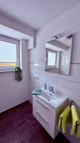 a white bathroom with a sink and a mirror at Ferienwohnung im Ellertal in Bockelnhagen