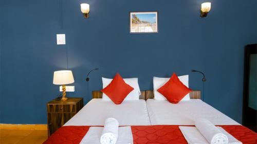 a blue bedroom with a bed with red pillows at Shelter Guest House in Candolim