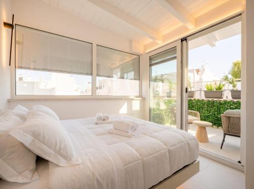 a white bedroom with a large bed and a balcony at Chiantera in Polignano a Mare