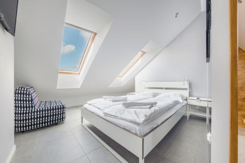 a white bedroom with a bed and a chair at Jantar Park in Jantar