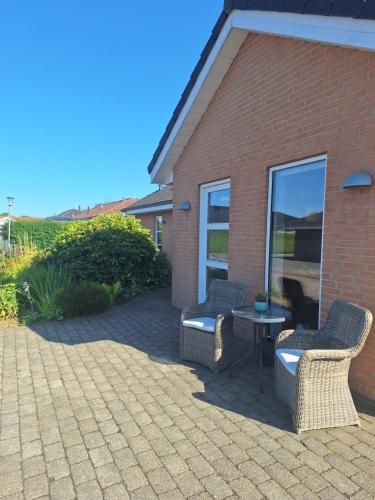 a patio with two chairs and a table in front of a building at Nice room with a wonderful view in Sommersted