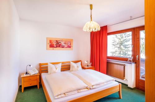 a bedroom with a large bed with a red curtain at Sporthotel Pechtl in Lermoos