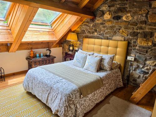 a bedroom with a bed and a stone wall at El Molino de la Ropería in Serrilla