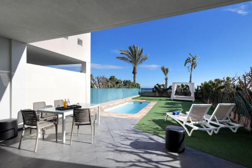 a patio with a table and chairs and a swimming pool at Villas Eurostars Las Salinas in Caleta De Fuste