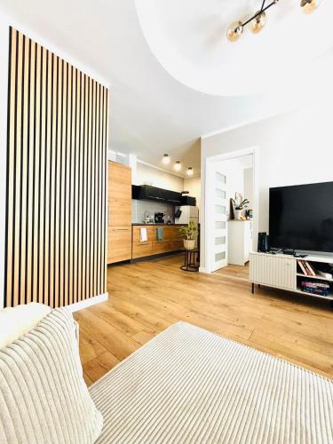 a living room with a large television and wooden floors at Sowia Przystań in Nowa Ruda