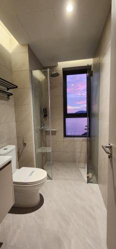 a bathroom with a toilet and a window at 4BR Beachfront Pantai Cenang Langkawi in Pantai Cenang