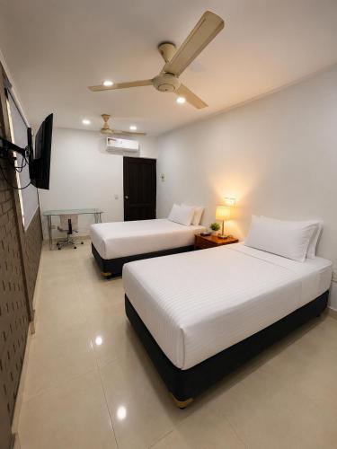 two beds in a hotel room with a tv at Hotel Luna Del Rio in Puerto Salgar