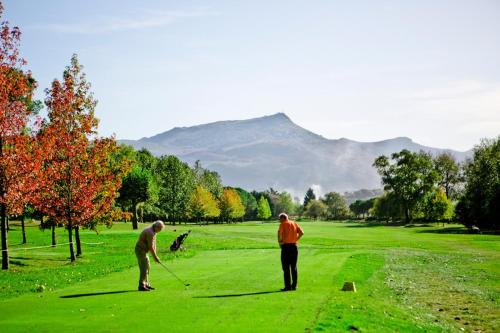 two men playing golf on a lush green field at Hotel Colbert in Saint-Jean-de-Luz