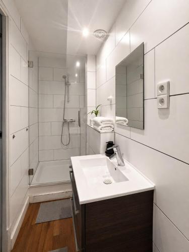 a white bathroom with a sink and a shower at La Belle Heure B&B - formerly Huis van Steen - in Lelystad