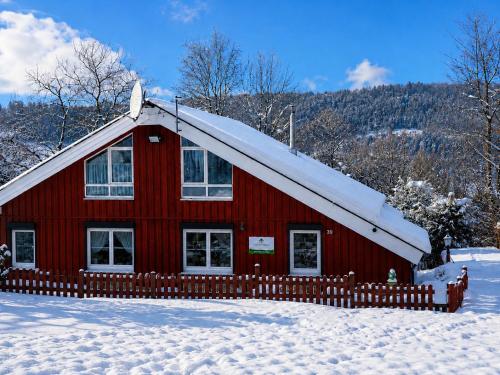 a red barn with a snow covered roof in the snow at Haus Waldblick in Extertal