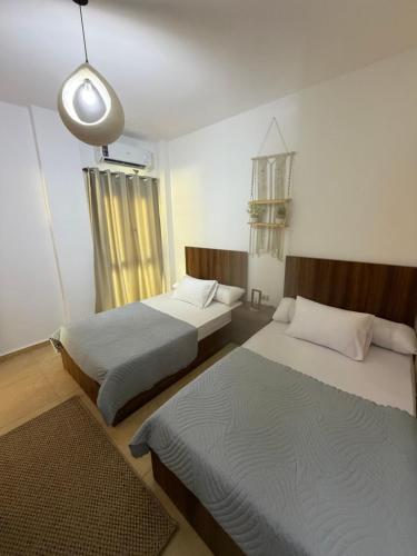 a bedroom with two beds and a light fixture at Ghazala valley ground floor in El Alamein