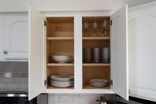 a kitchen cabinet filled with plates and glasses at Private Heated Pool House with Sauna CL in Crystal Lake