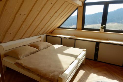 a bed in a room with a large window at Chaty Korňa in Predmerská