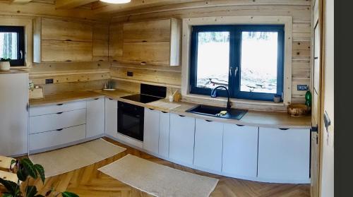 a kitchen with white cabinets and a sink and a window at Chaty Korňa in Predmerská