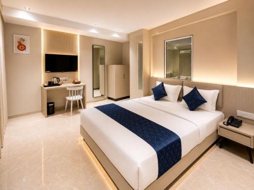 a hotel room with a large bed and a kitchen at Fun Hotels Gandhinagar in Gandhinagar