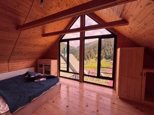 a woman laying on a bed in a room with a large window at Bakhmaro Eco Cottage in Chʼkhakoura