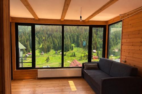a living room with a couch and a large window at Bakhmaro Eco Cottage in Chʼkhakoura