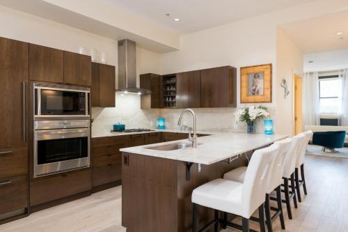 a kitchen with wooden cabinets and a kitchen island with white chairs at Leadville Penthouse #8 in Ketchum