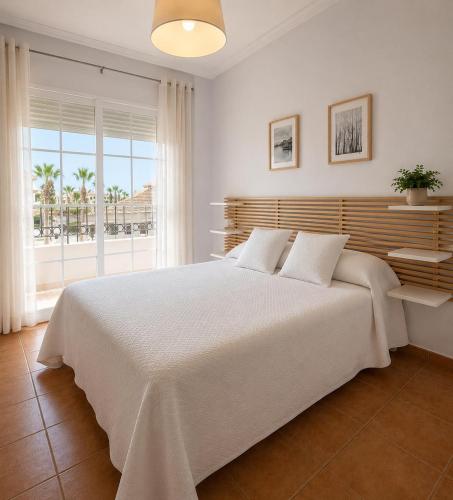 a white bedroom with a large white bed and a window at Urban Suite in Los Alcázares