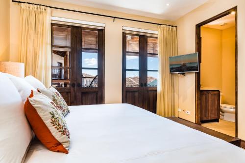 a bedroom with a bed and a tv and windows at Las Catalinas Doorway in Playa Flamingo