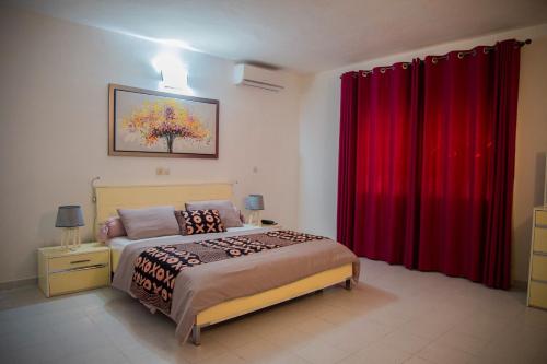 a bedroom with a bed with red drapes at Résidence Touraco in Abidjan