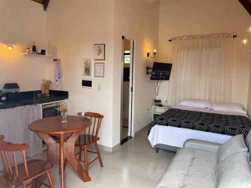 a bedroom with a bed and a table and a kitchen at Jacuzzi Privativa, Chalé Romântico com Decoração in Monte das Gameleiras