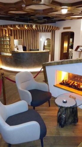 a lobby with chairs and a table and a fireplace at Hotel Patrizia Dolomites Glamour in Moena
