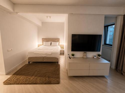 a bedroom with a bed and a flat screen tv at Cortina North Luxury Studio in Voluntari