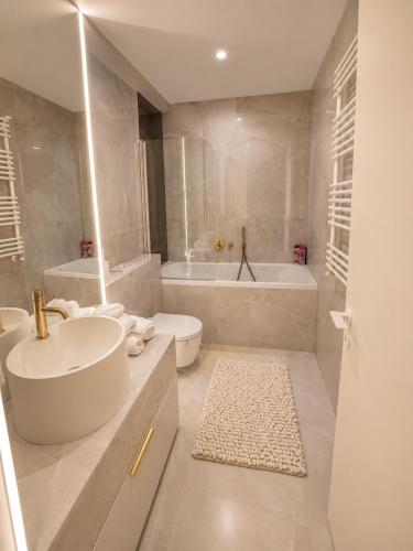 a bathroom with a sink and a tub and a toilet at Cortina North Luxury Studio in Voluntari