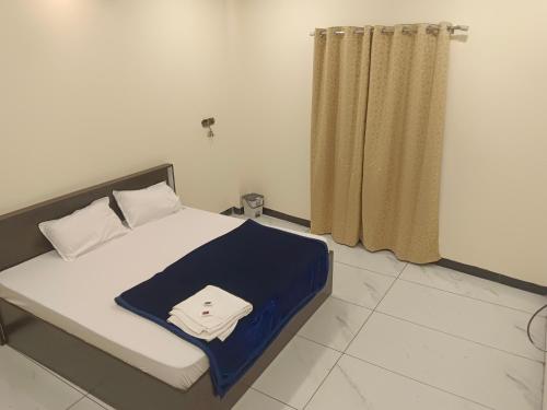 a bedroom with a bed with a blue blanket on it at Hotel Bhagwati Palace in Ujjain
