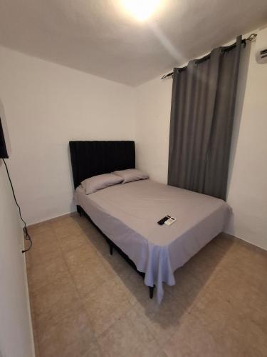 a small bedroom with a bed with a gray curtain at Acogedor Departamento Entero in Hornillo