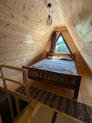 a bed in a wooden room with a window at Prenoćište Lelić in Valjevo