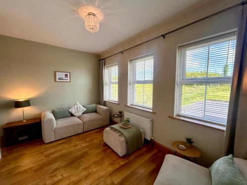 a living room with a couch and two windows at Fairy Fort View, Lahinch in Carrowauff