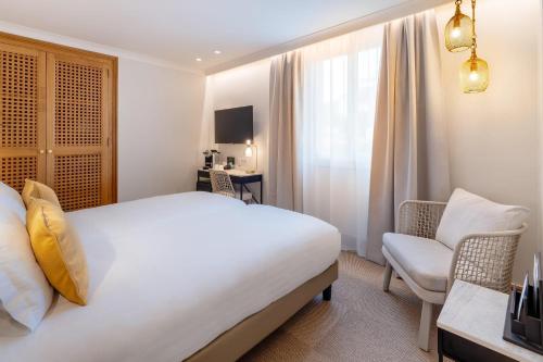 a hotel room with a bed and a chair at Best Western Premier Montfleuri in Sainte-Maxime