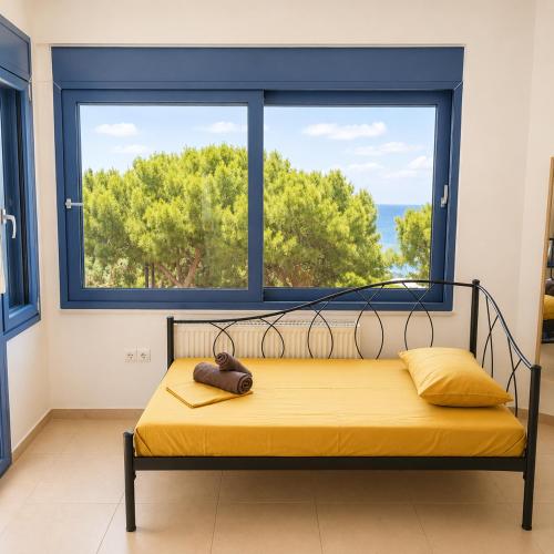 a bed in a room with a large window at Schinos Salty Studio in Vathí