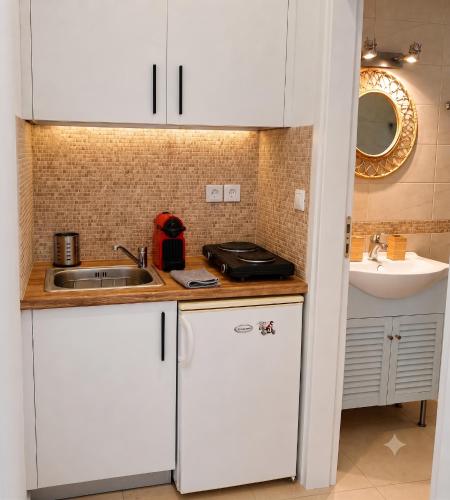 a kitchen with white cabinets and a sink at Schinos Salty Studio in Vathí