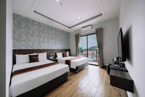a hotel room with two beds and a television at catba new city hotel in Cat Ba