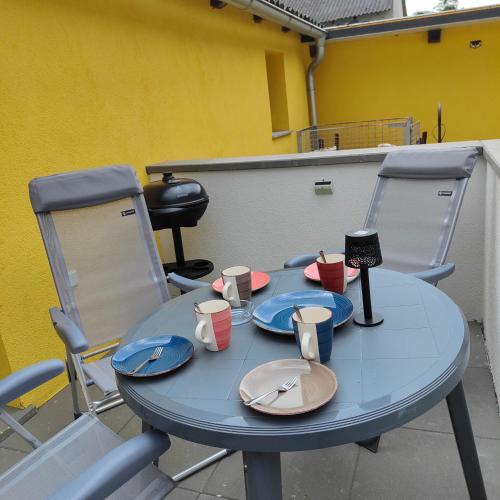 a blue table with plates and cups and two chairs at Ferienwohnung Einsiedler - für 4 Personen mit Terrasse und Grill in Windisch Minihof