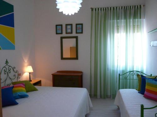 a bedroom with two beds and a window with a chandelier at Appartamento Tino in Castiglione della Pescaia