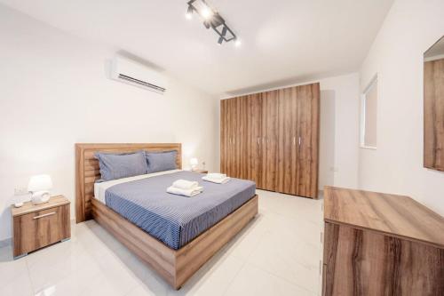 a bedroom with a king sized bed and wooden cabinets at Sandy Soul in Birżebbuġa