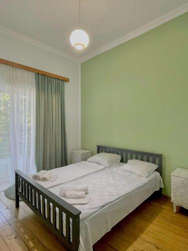 a bedroom with a bed with white sheets and a window at Guest House Germani in Telavi