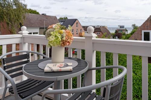 a table with a vase of flowers on a balcony at Buhne 3 in Grömitz