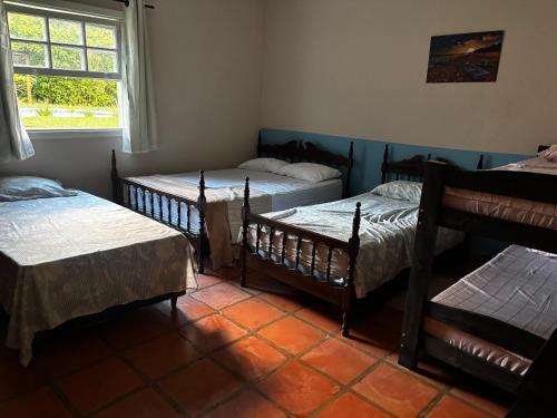 a room with four beds and a window at Villa Dona Jaca - Casa da Mata - Casa 02 in Socorro