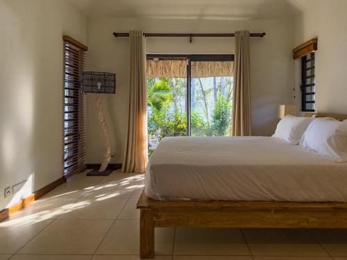 a bedroom with a bed and a large window at Beachfront Villa with Pool & Sunset Views in Rivière Noire