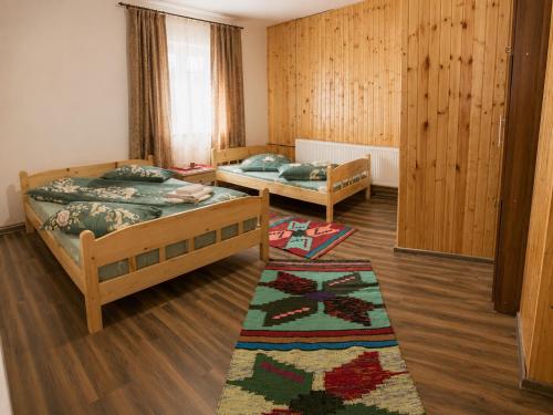 two beds in a room with wooden walls and wooden floors at Cabana Elena in Gârda de Sus