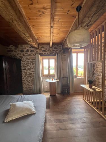a bedroom with a bed and a table and windows at La Maison du Tisserand maison entière à Bécherel in Bécherel