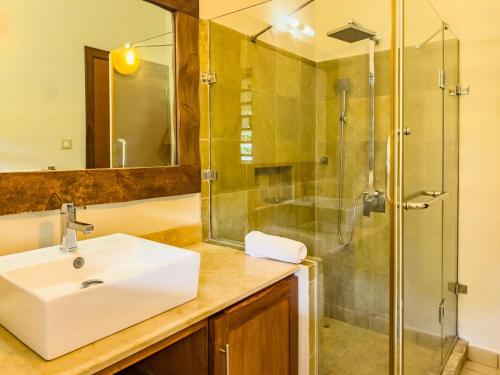 a bathroom with a sink and a shower at Beachfront Villa with Pool & Sunset Views in Rivière Noire