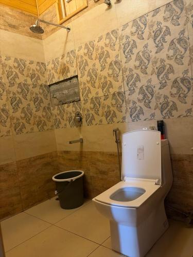 a bathroom with a toilet and a trash can at IBP Estate in Rānīkhet
