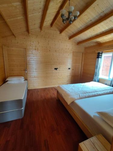 two beds in a room with wooden walls and wood floors at IBP Estate in Rānīkhet