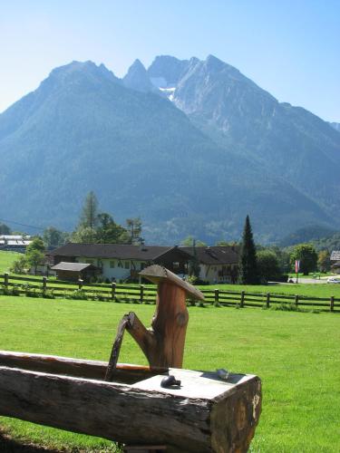 a wooden bench in a field with mountains in the background at Landhaus am Waldrand in Ramsau
